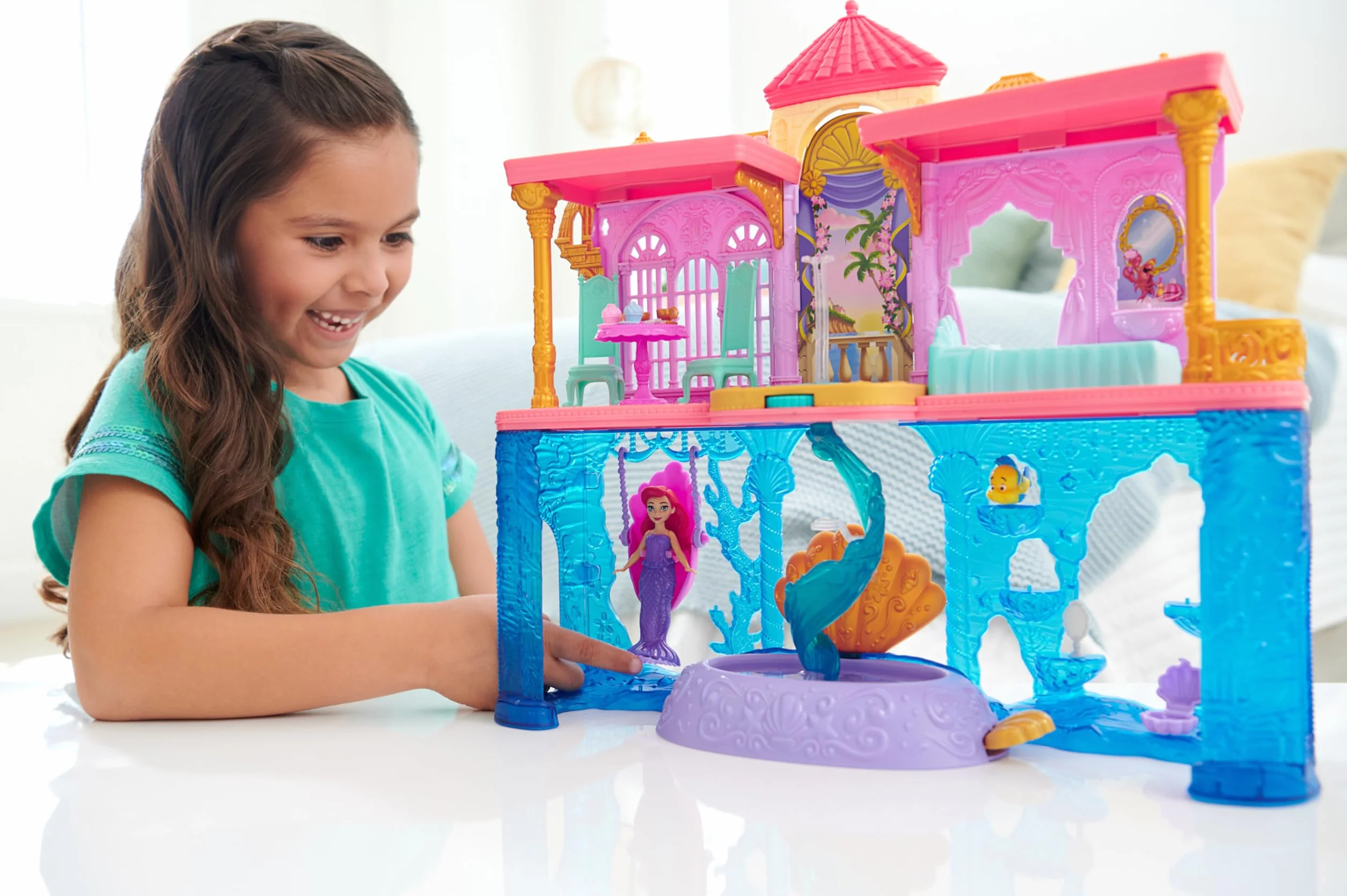 Mattel Księżniczka Disneya Pałac Arielki Domek dla lalek, mała lalka, 1 figurka przyjaciela, 12 elementów, 6 obszarów zabawy i basen, inspirowany filmem Disneya HLW95